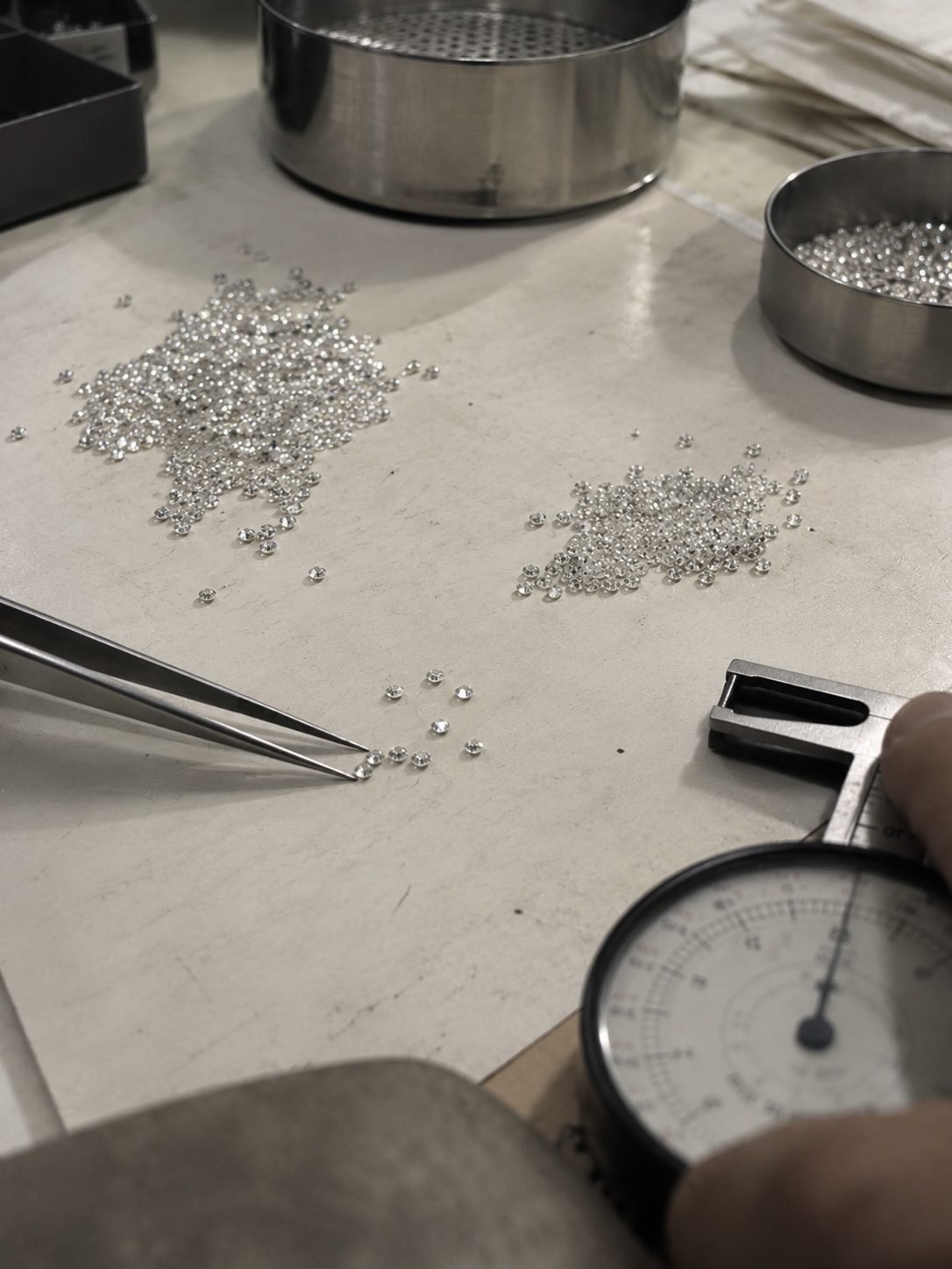 Melee diamonds being measured and sorted on a workbench